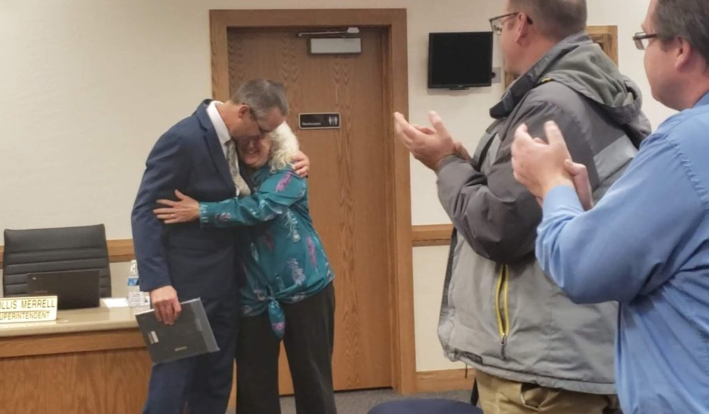 Photo by Amanda NicholsSuperintendent Hollis Merrell (left) and long-time co-worker CC LaGrange (right) share a hug after an appreciative speech by Merrell while attendants of the meeting applaud.