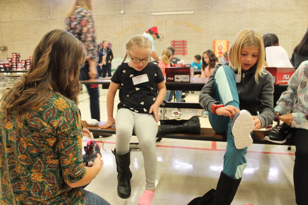 Photos by L. ParsonsEmerson Leonard (left) gets some help from teacher Stephanie Westover trying on her new shoes as Mia Hartnet (right) does the same.