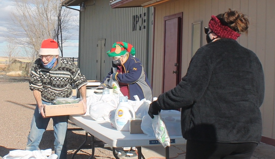 Photo by China CassidyOn Saturday, Dec. 19, members of the Holbrook Elks Lodge handed out bags of toys, food boxes and gift cards that can be used to help purchase shoes and coats from Walmart to 50 families for the holidays. Pictured are Beverly Goodnight (center) who handed out hot dogs to families waiting in line while Phil Cobb (left) handed out the supplies along with Kassandra Grabowski (right).