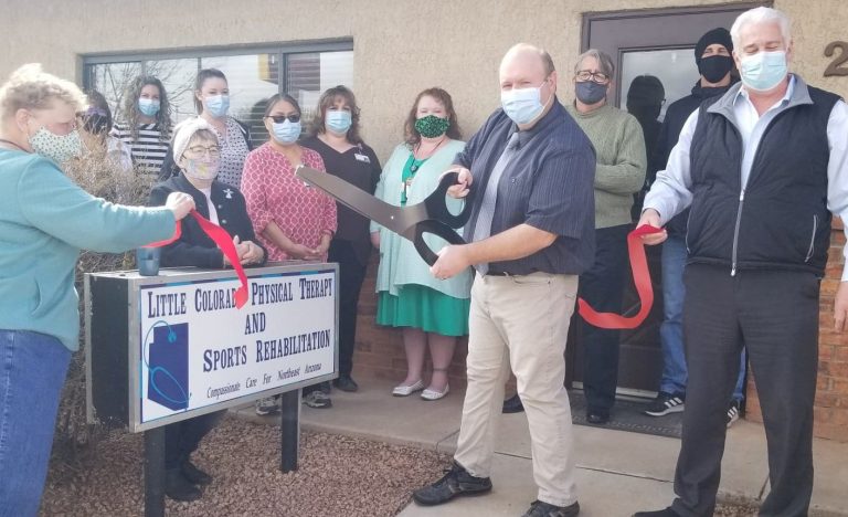 Photo by L. ParsonsLittle Colorado Medical Center Chief Financial Officer Janice Freet (left) and Chief Ancillary Officer Doug Umlah (right) hold the ribbon as Joey Hartnett (center) cuts it for the new Little Colorado Physical Therapy and Sports Rehabilitation Center in Winslow. Taking part in the event are members of the Winslow Chamber of Commerce. The center, formerly owned by Hartnett became part of the LCMC family on March 1.