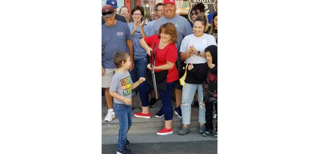 Photo by L. ParsonsFlatbed Ford Bed and Breakfast, located at 214 N. Kinsley Ave. in Winslow celebrated their grand opening last Saturday. Here, proprietor Sonja Ybarra holds the ribbon cutting scissors as her supporters and family look on. The picture includes (left to right) Raymond Martinez, Brax Moncayo (front), Debbie Martinez, Tommy Martinez, Ybarra, Gary Ybarra, Jessica Moncayo and Gunner Moncayo. Members of the Winslow Chamber of Commerce and City Council were also in attendance.