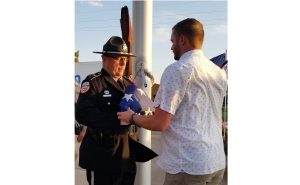 Photo by L. ParsonsThe community of Winslow came together, approximately 300 strong to memorialize the 20-year anniversary of the Sept. 11 attacks. Here, Casey Hancock (right) receives a flag from Sheriff’s deputy Ron Chisolm. Hancock is the grandson of the late Dale Hancock who was instrumental in bringing pieces of the Twin Towers to the Winslow Memorial Garden on Third Street.