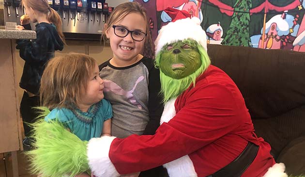 Photo by Linda KorYou know the holiday season has arrived when the Grinch begins making the rounds. Last Saturday he visited with kids at Esther’s Diner as part of the Joseph City Market held there each month. Here Beatrice (left) and Mina (center) Colligon visit with the Grinch, letting him know all that they hope for this holiday season.
