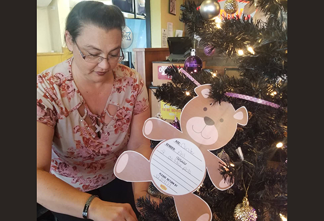 Photo by L. ParsonsWinslow Denny’s General Manager and member of The Cherry Bombs, Jennifer McNair places ornaments on a holiday tree. Guests are encouraged to take a tag from the tree and fulfill the wish to assist Alice’s Place this season.