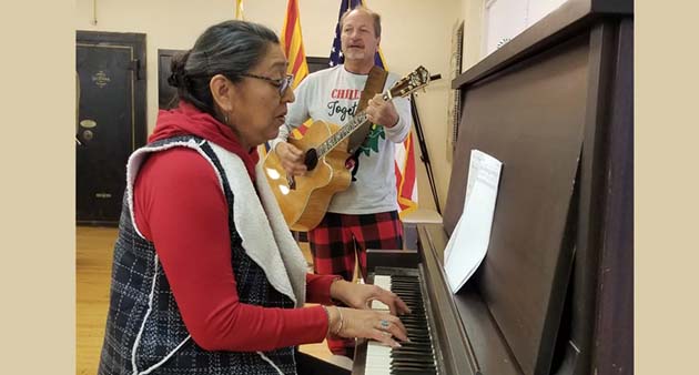 Photo by L. ParsonsGreg Hackler (standing) and Denise Estudillo led attendees of the latest Good Morning Winslow in Christmas Carols following the presentation from Economic Development Director Una Wirkebau.