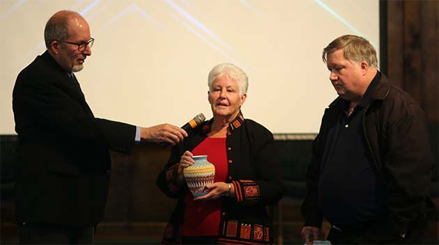 HIS Principal Pedro Ojeda (left) presents student made pottery and a plaque to Bev Benson (center) and her son Ted Benson (right) for the school’s water well project in memory of husband and father Ted Benson.