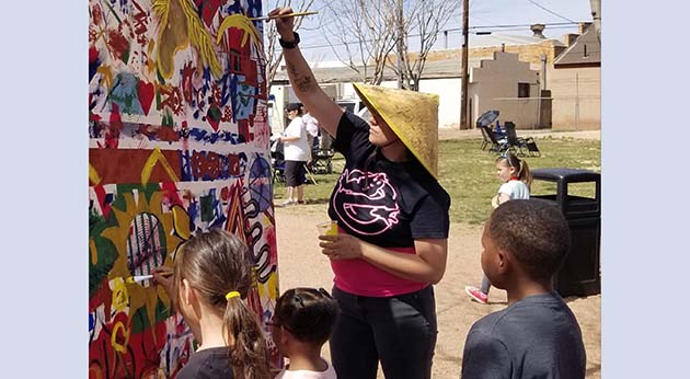 Photo by L. ParsonsWinslow’s Music in the Park held last weekend brought out the crowds. Here Winslow Arts Council member Cheri Russell (right) joined kids to add to the ongoing mural the council has been working on. Each Saturday in March, the canvas has been set up on the corner and everyone was invited to paint on it with one specific color. The piece will be displayed in a city building when it is completed.