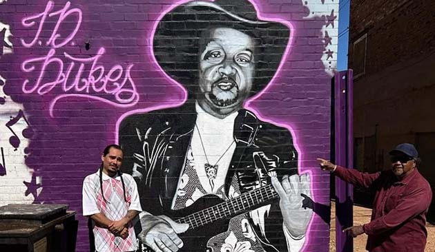 Photo by Shawn WhiteArtist Jorge Olivas (left) standing with Tommy Dukes (right) in front of the mural Olivas created to honor his friend.