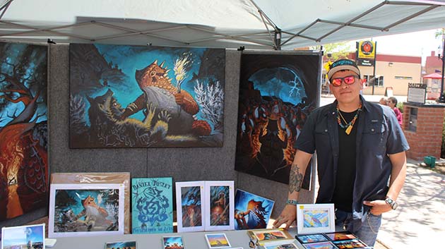 Photo by Shawn WhiteDaniel Josley posed with his signature horned lizard paintings at the Winslow Arts Festival.